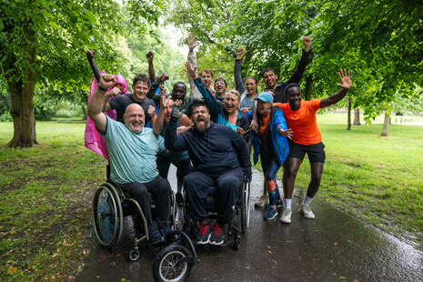 Eine Gruppe von Menschen mit verschiedenen Hautfarben und Behinderungen steht zusammen und freut sich.