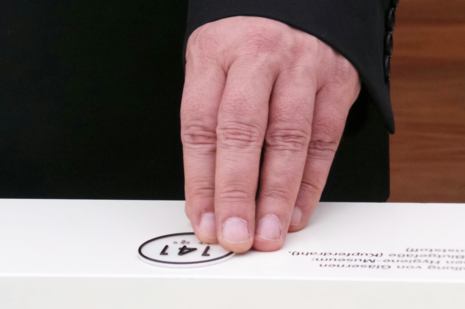 Eine Hand erfüllt eine Markierung in Brailleschrift